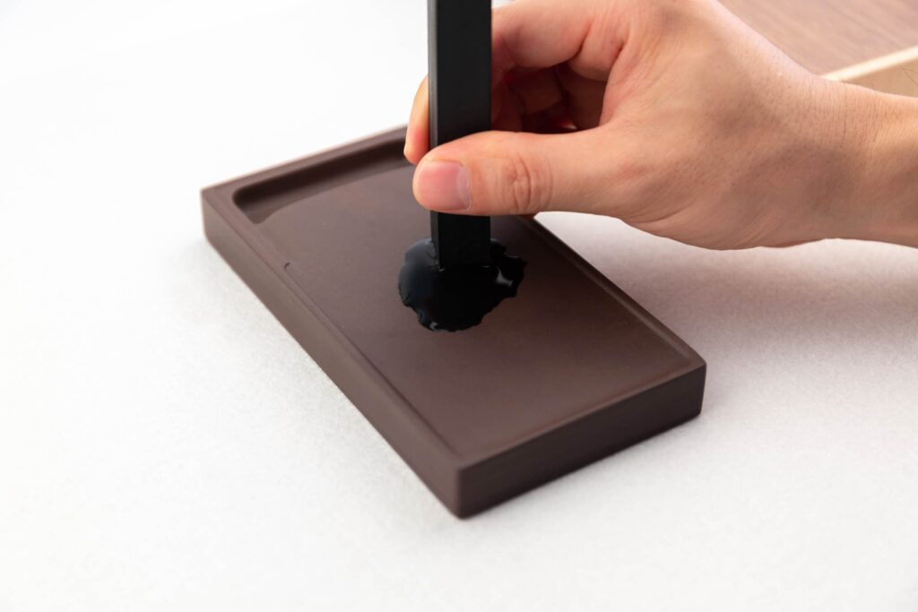 硯台裏滴幾滴水,用墨條打圈或來回推以獲得墨汁。